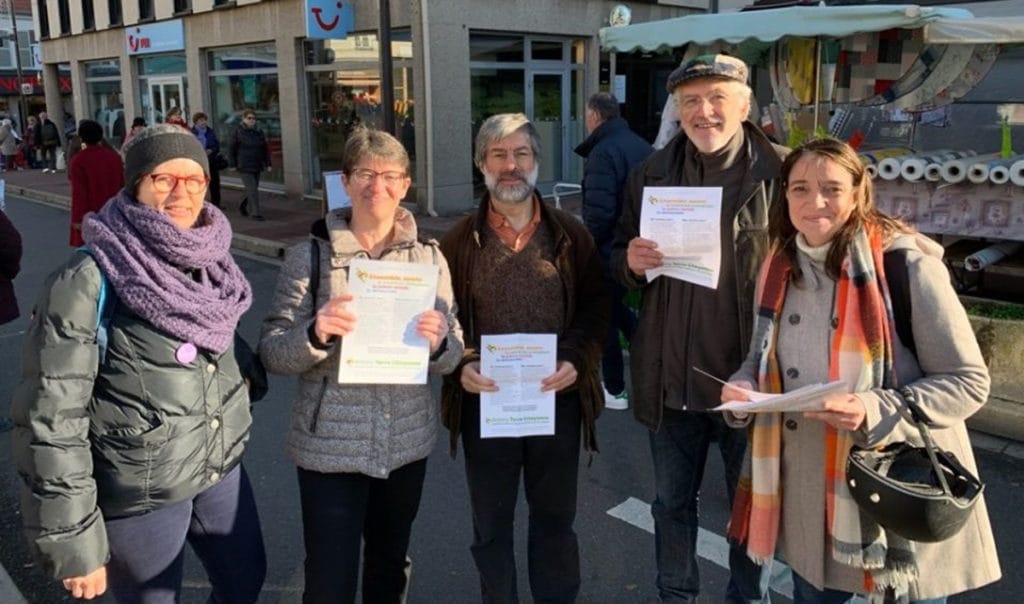 Cinq militantes et militants du collectif, tracts en main, devant les étals d’un marché d’Antony.