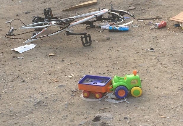 Un vélo abîmé et un tracteur jouet abandonnés sur la terre battue, après l’expulsion du 28 juillet 2020.
