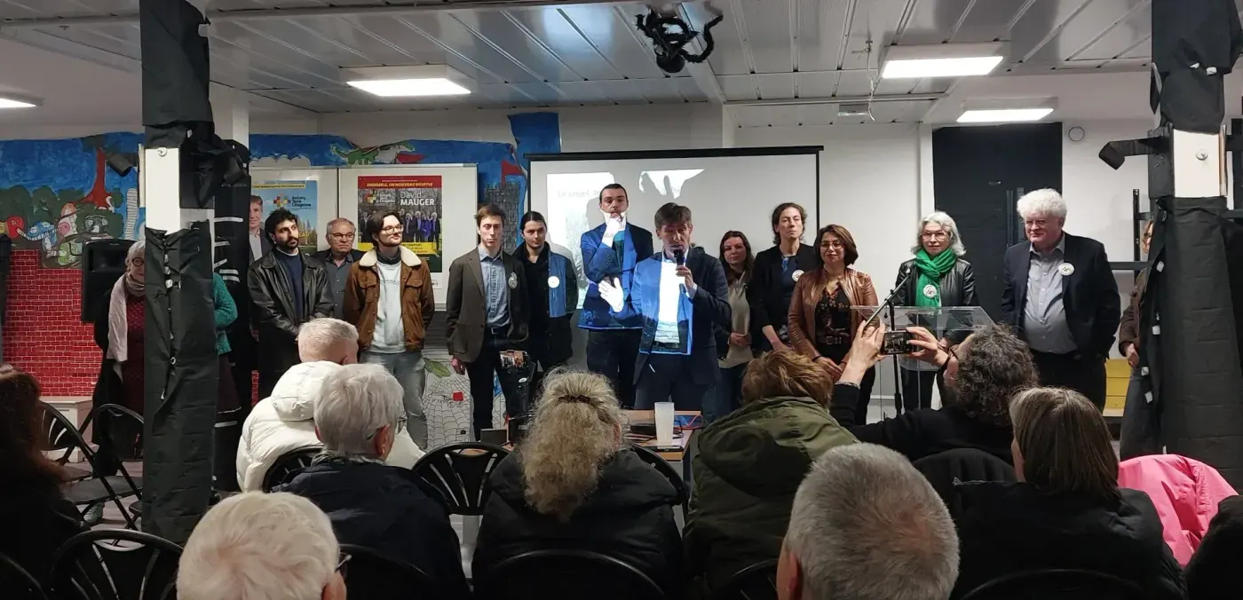 Une douzaine de membres du collectif debout devant le public, David Mauger au micro