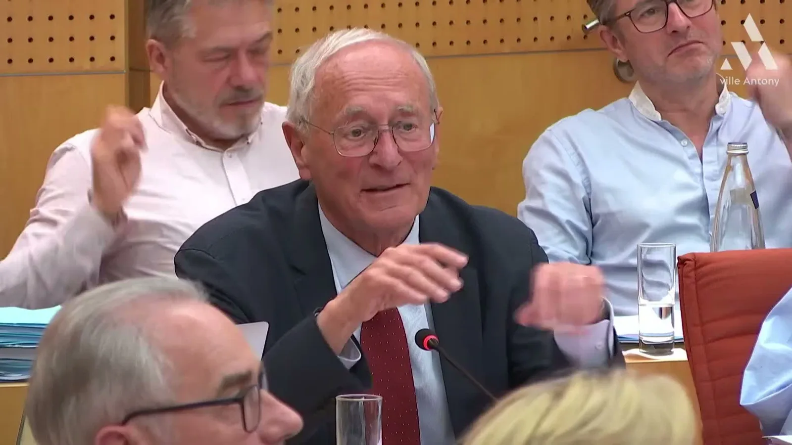 Jean-Yves Sénant intervient au micro, assis au milieu des conseillers municipaux.